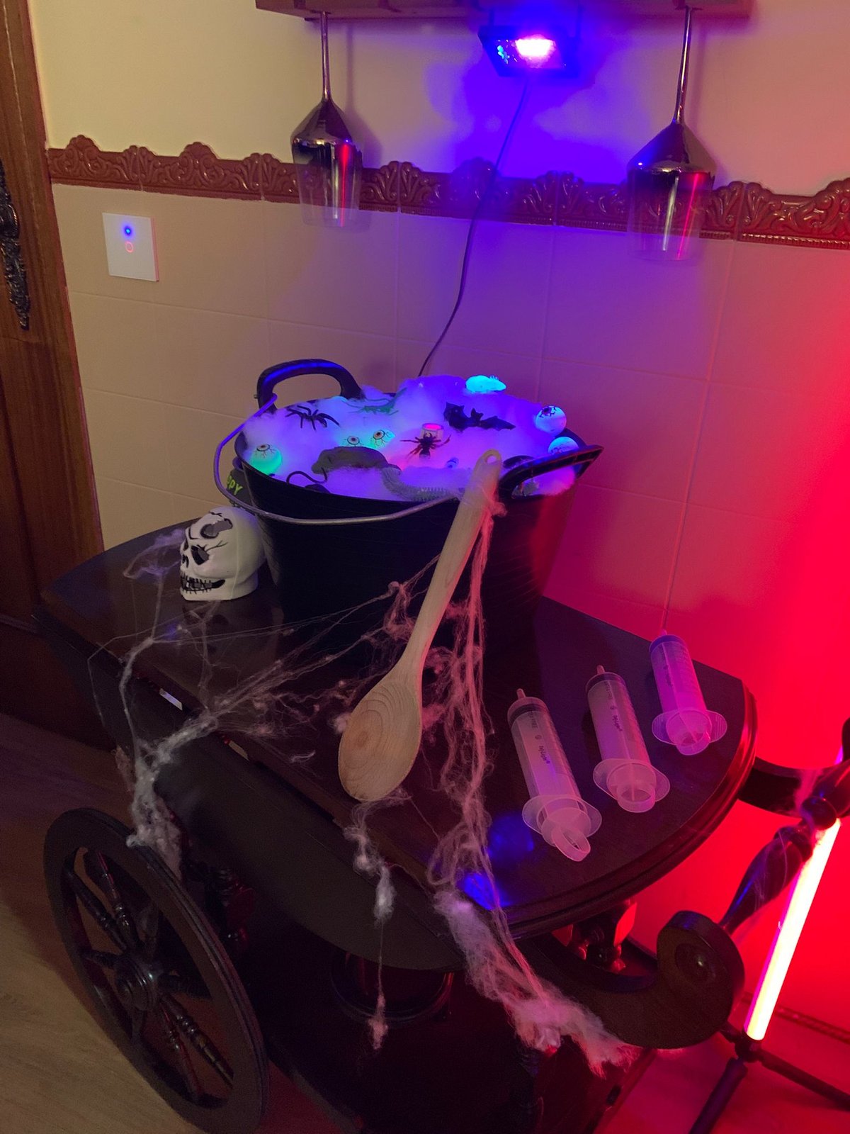 Caldeirão com fumo e luz vermelha, rodeado de peças de Halloween